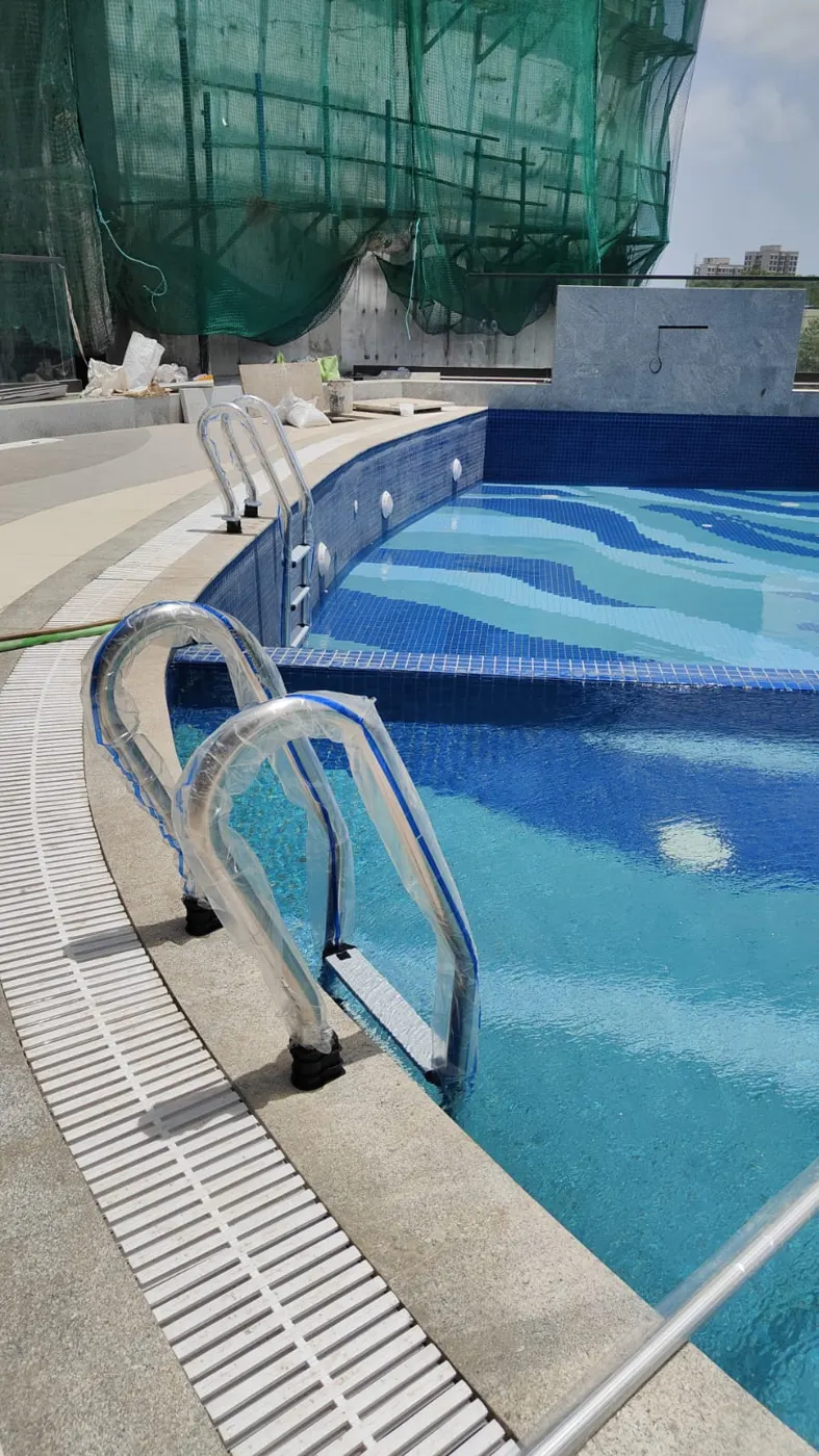 Swimming pool nearing completion with blue mosaic, entry steps and stainless steel ladders